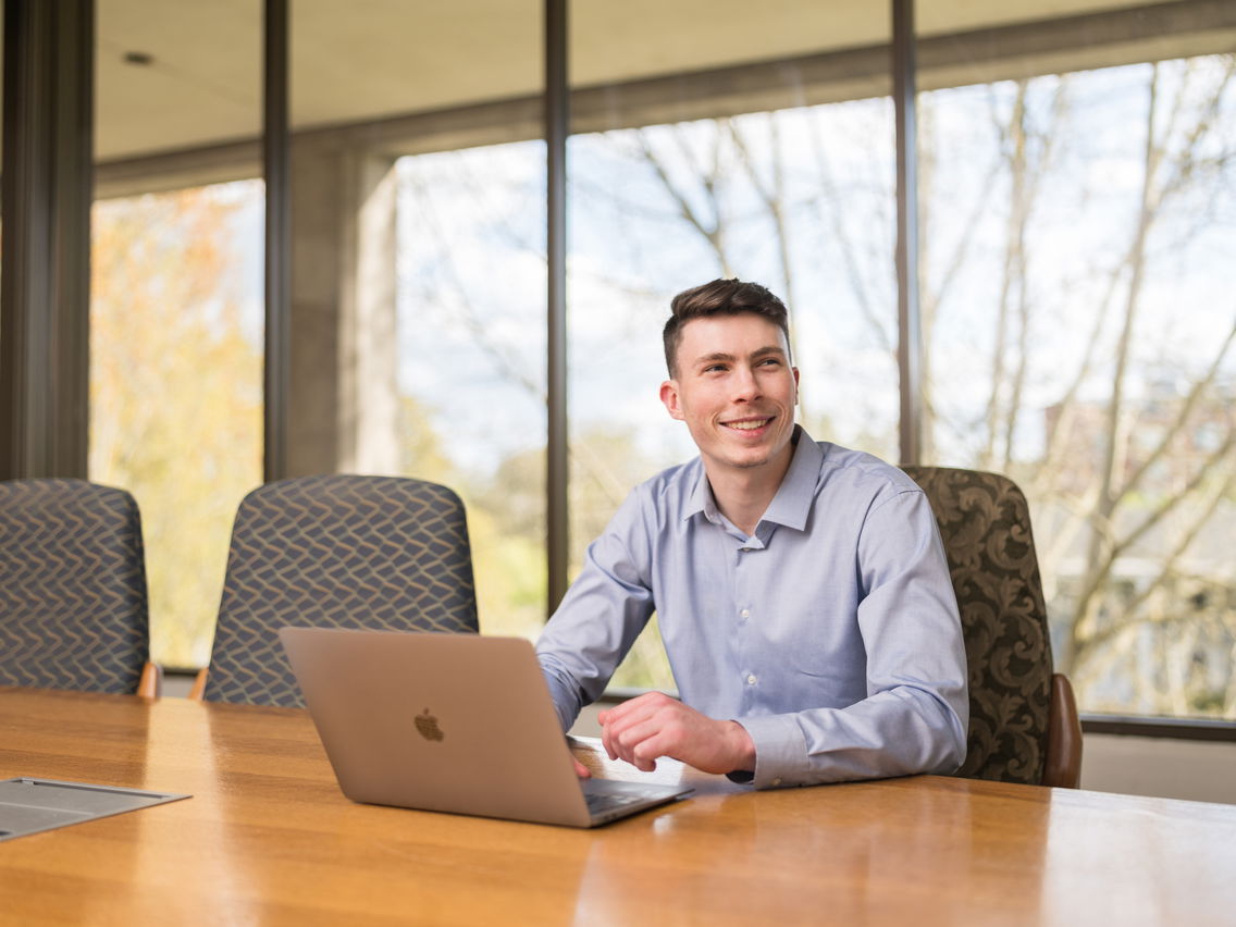 Student sitting at conference room table with a laptop