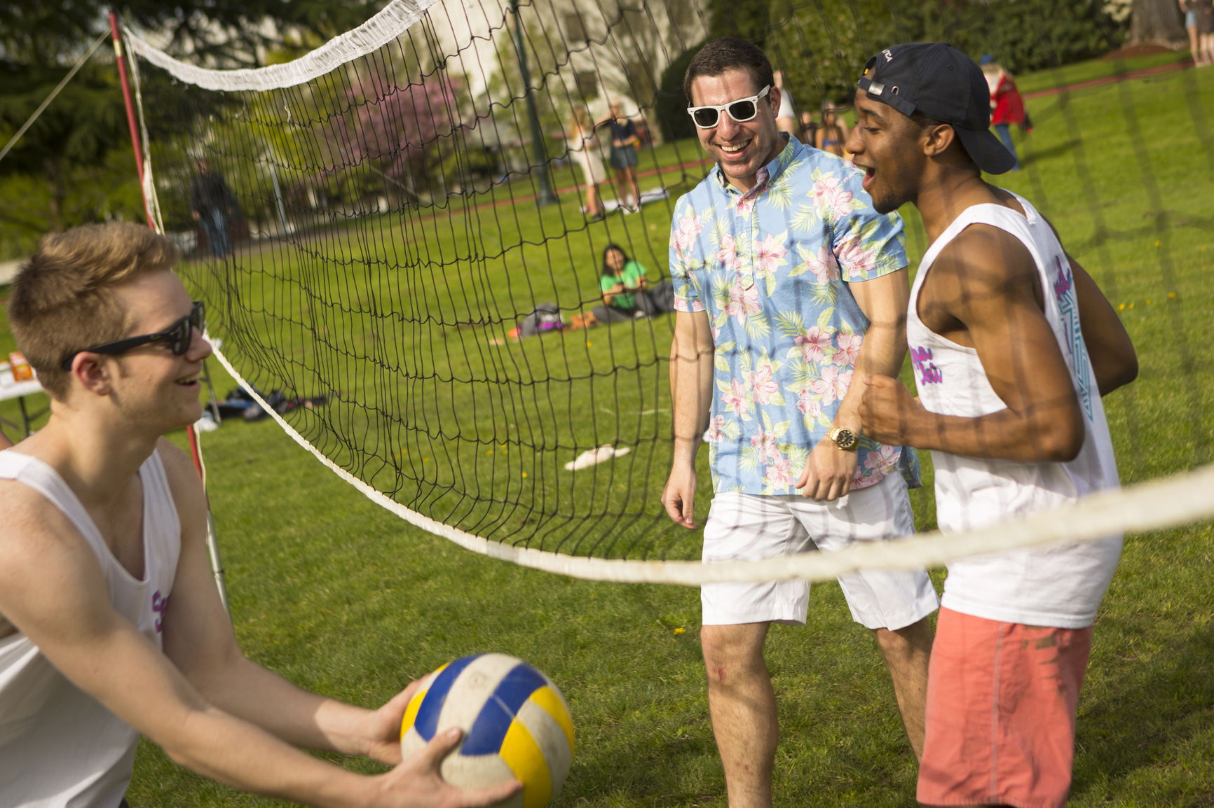 3 students playing volleyball on the quad. 